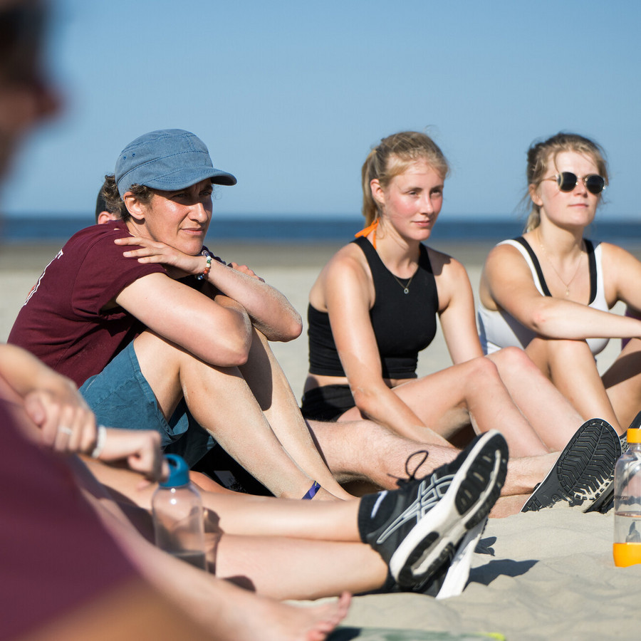 Jugendliche sitzen gemeinsam am Strand und wirken nachdenklich