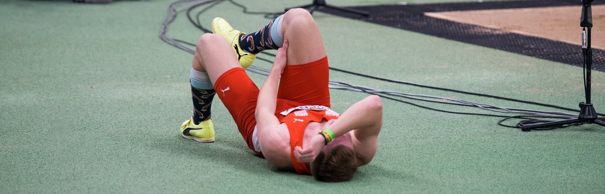 Sportler liegt auf dem Boden und hält sein Bein fest, er hat sichtlich schmerzen