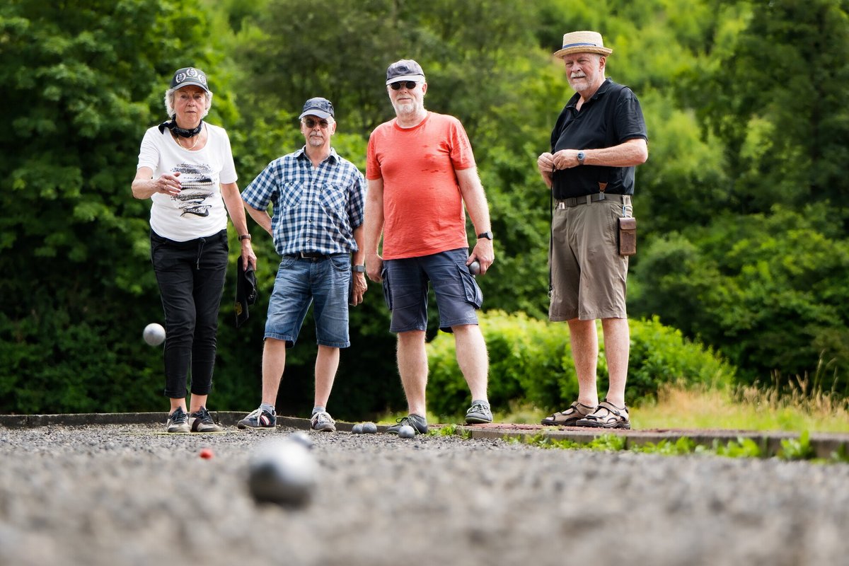 vier Ältere Personen spielen draußen Boule